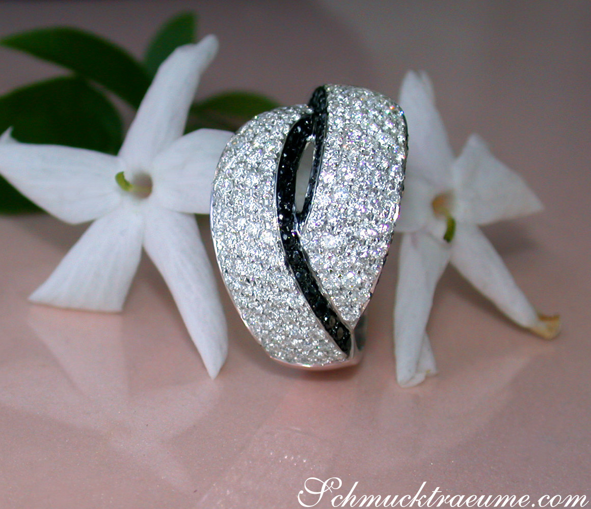 Klassischer Brillantenring mit schwarzen Diamanten, Detailaufnahme auf weißem Blütenhintergrund