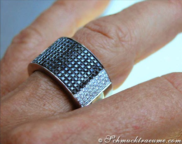 Schwarzer Bandring mit Diamanten, Detailaufnahme auf Handfinger, glänzende Steine