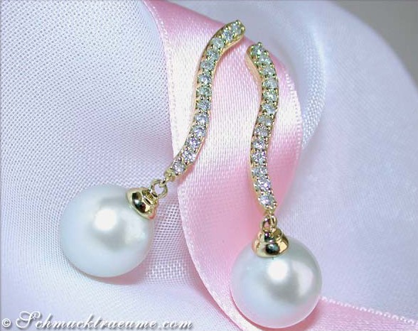 Gelbgold-Ohrringe mit Südseeperlen und Brillanten, sanfte Formen, elegant auf Satin liegend.
