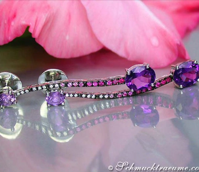 Edle Ohrstecker aus Weißgold mit Amethysten, Rubinen & Saphiren, auf glänzender Oberfläche Edle Ohrstecker aus Weißgold mit Amethysten, Rubinen & Saphiren, auf glänzender Oberfläche