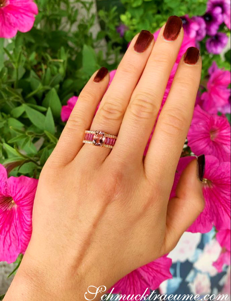 Exquisiter Morganit-Ring mit pinken Saphiren und Brillanten auf Hand vor Blumen