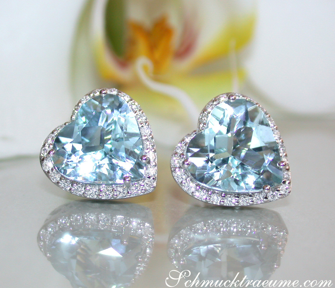 Herzformige Aquamarin-Ohrstecker mit Diamant-Halbkreis, vor Orchidee.