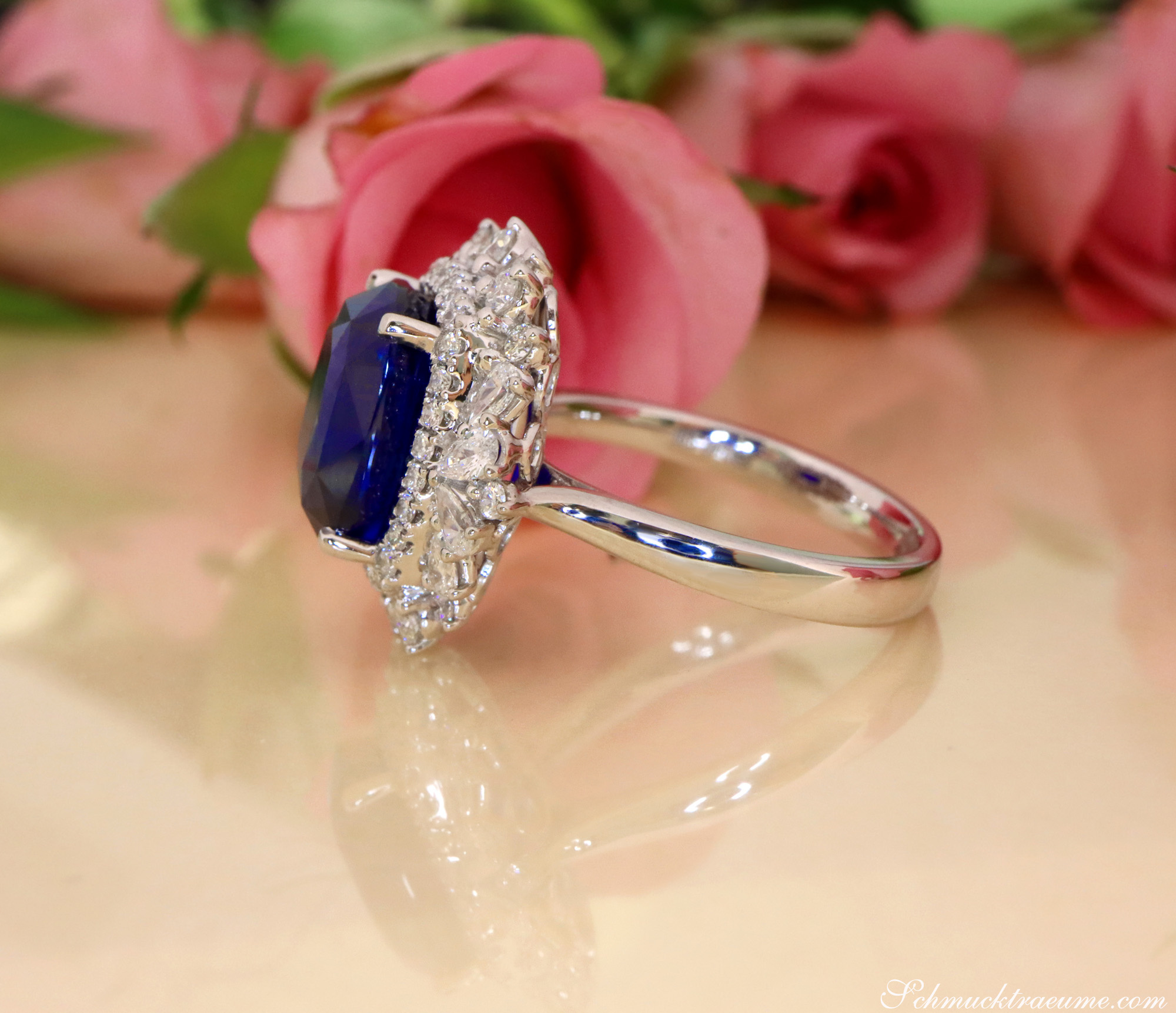 Saphir-Ring mit Diamanten in Weißgold, Detailaufnahme mit Rosen im Hintergrund
