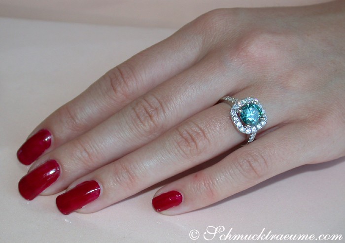 Blauer Diamant Solitär Ring auf handlanger Hand mit roten Nagellack.