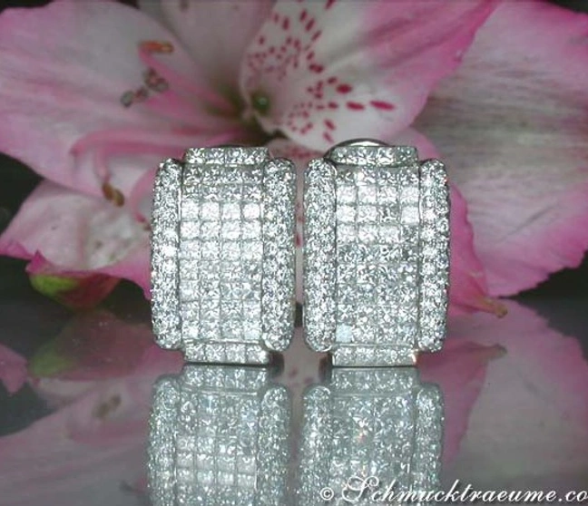 Diamantohrringe mit Invisibleset in Weißgold, vor rosa Blüten, Detailaufnahme Diamantohrringe mit Invisibleset in Weißgold, vor rosa Blüten, Detailaufnahme