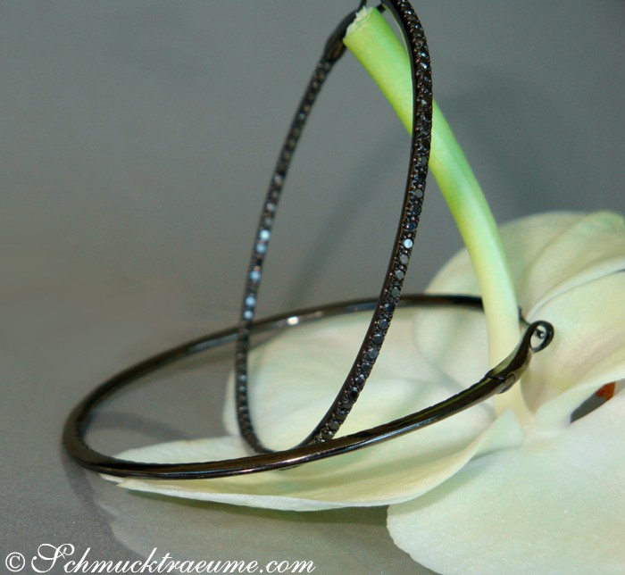 Schmuckcreolen mit schwarzen Diamanten auf Orchideenblüte, elegant und auffällig.