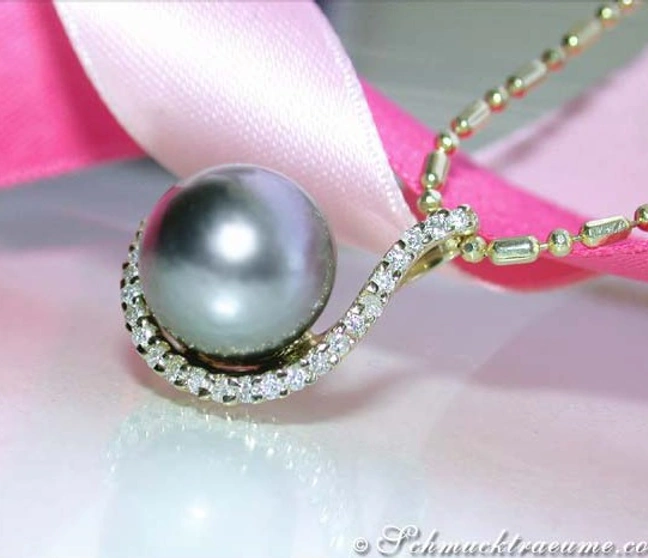 Tahitiperlen-Anhänger mit Brillanten in Gelbgold, detailreich, elegant, auf rosa Satin liegt. Tahitiperlen-Anhänger mit Brillanten in Gelbgold, detailreich, elegant, auf rosa Satin liegt.