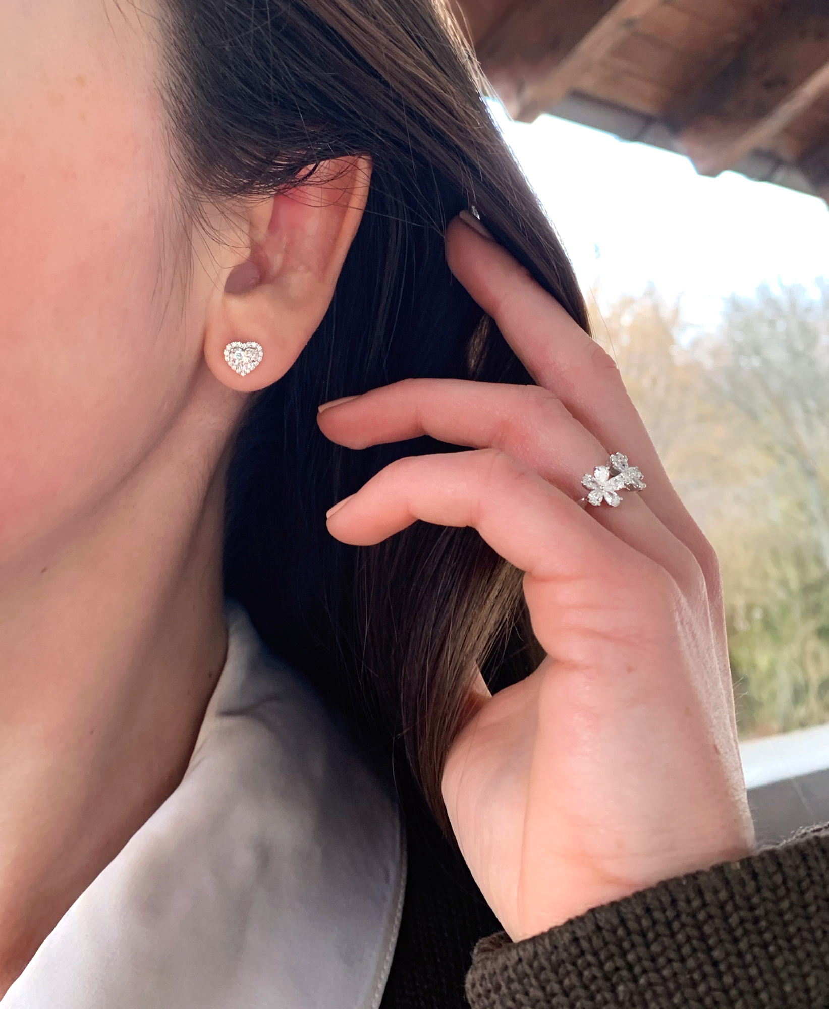 Weibliche Ohrstecker mit funkelnden Diamantenherzen in Herzschliff, Detailaufnahme.