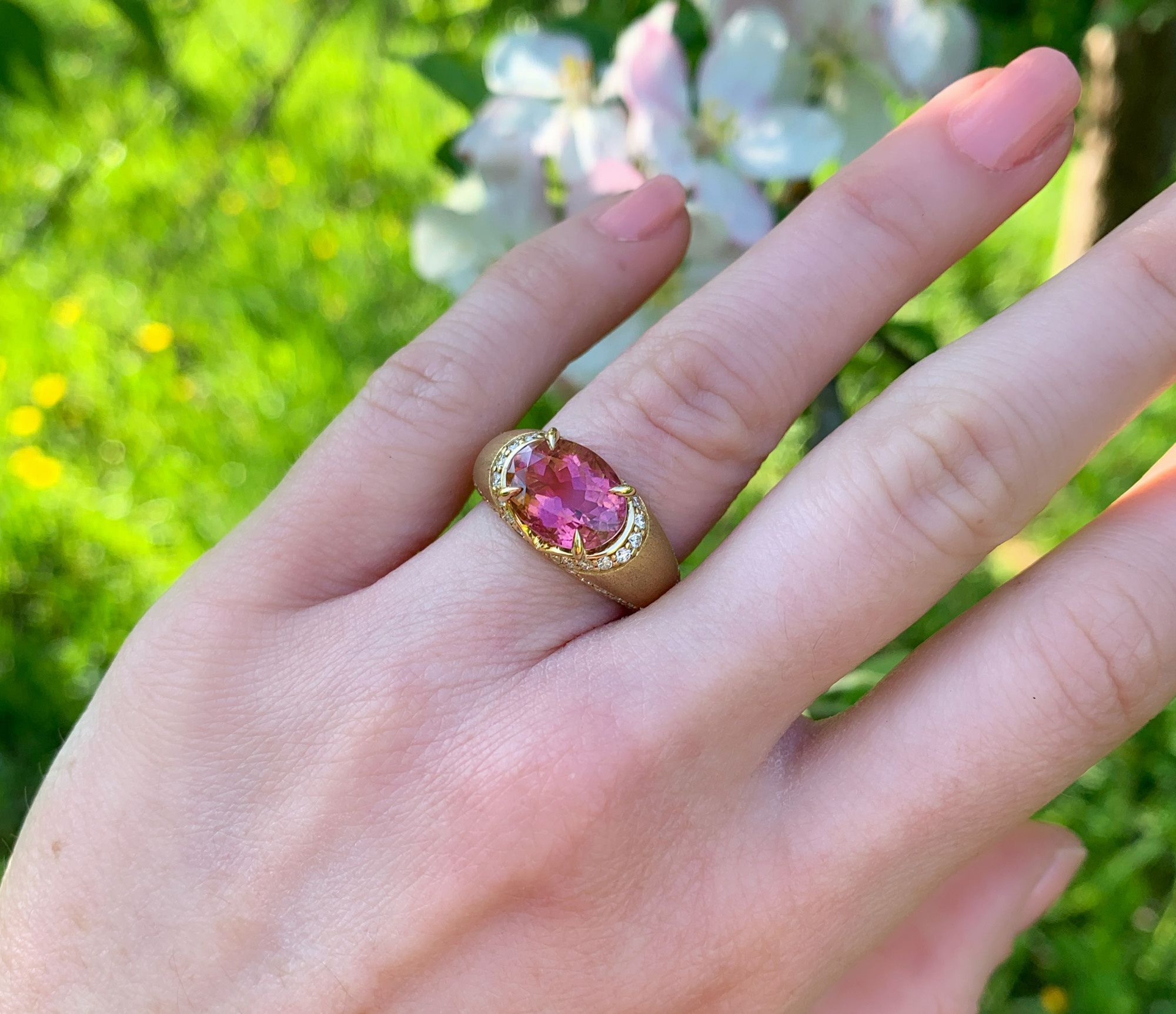 Rosa Turmalin Brillanten-Ring im Gelbgold 750, Detailaufnahme im Freien bei Blumen.