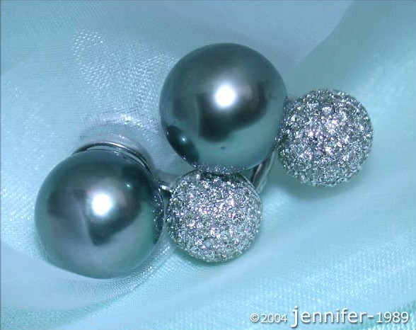 Detailansicht von Tahitiperlen-Ohrsteckern mit Brillanten-Pavé, glänzende Oberflächen, auf glänzendem Stoff liegend