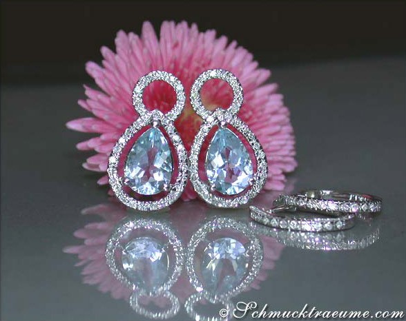 Weißgold-Ohrhänger mit Aquamarin-Tropfen und Diamanten, Detailaufnahme auf rosa Blume.