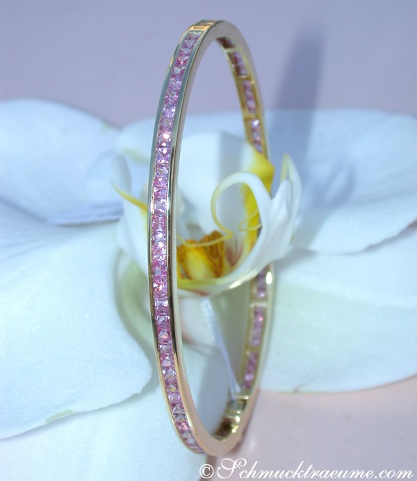 Goldener Armreif mit rosa Saphiren auf Orchideenblüte
