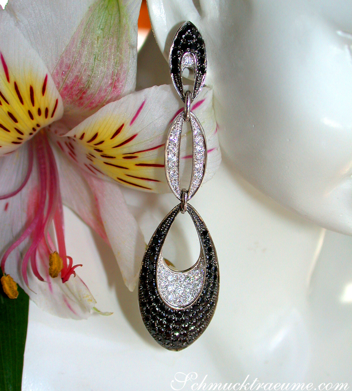 Schwarze Diamant-Ohrhänger mit weißen Diamanten, modernes Design, getragen auf weißem Hintergrund, Detailaufnahme.