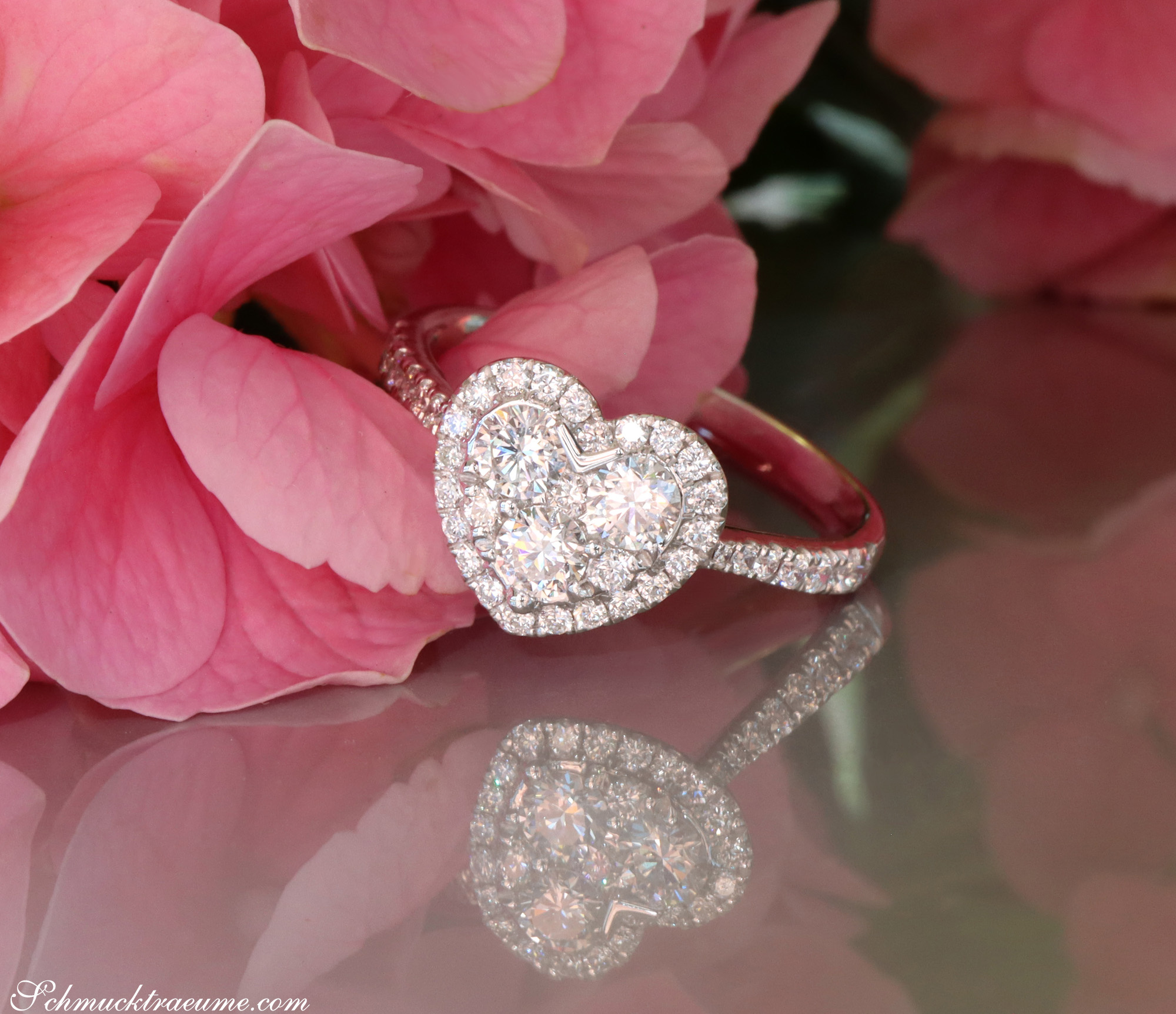 Herzring aus Weißgold mit Brillanten, Detailaufnahme auf Rosenblättern.