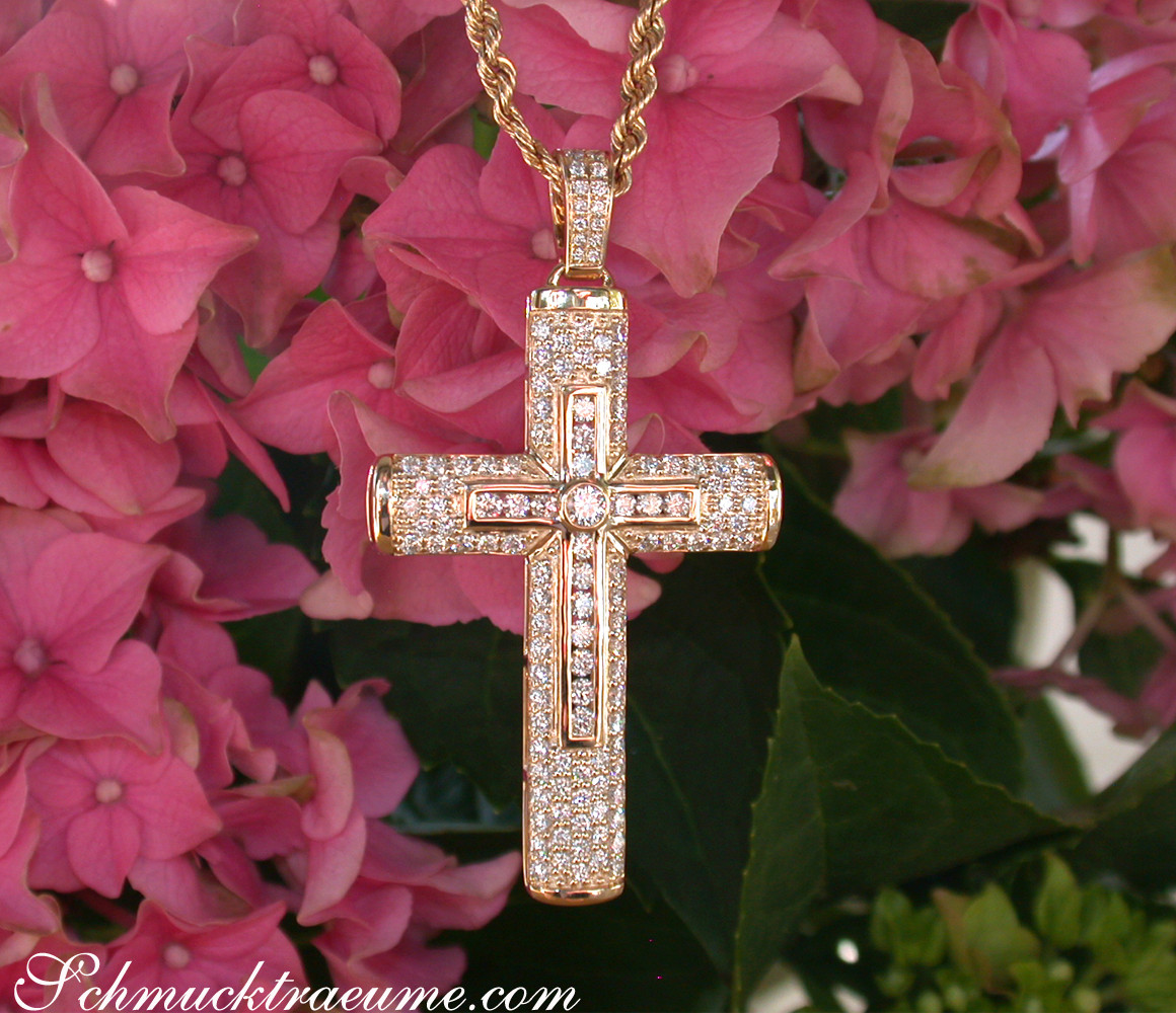 Goldener Kreuzanhänger mit Brillanten vor rosa Hortensienblüten