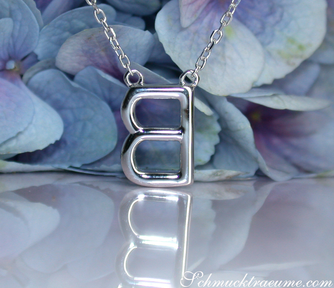 Zarte Halskette mit Brillanten-Initiale, Detailaufnahme, blühende Hortensien im Hintergrund