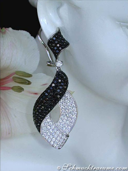 Schwarz-weiße Diamantohrringe auf Marmorkopf, Blüten im Hintergrund