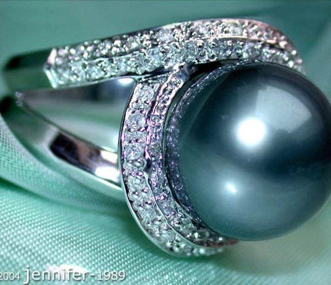 Stattlicher Tahitiperlen-Brillanten-Ring in Weißgold, Detailaufnahme, glänzende Perle, umgeben von Diamanten, auf grünem Stattlicher Tahitiperlen-Brillanten-Ring in Weißgold, Detailaufnahme, glänzende Perle, umgeben von Diamanten, auf grünem