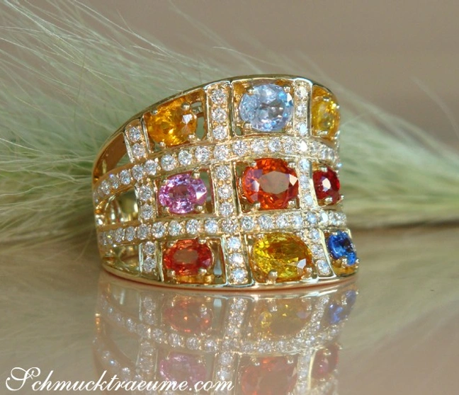 Goldener Ring mit Multicolor Saphir und Brillanten, Detailaufnahme, Feder im Hintergrund Goldener Ring mit Multicolor Saphir und Brillanten, Detailaufnahme, Feder im Hintergrund