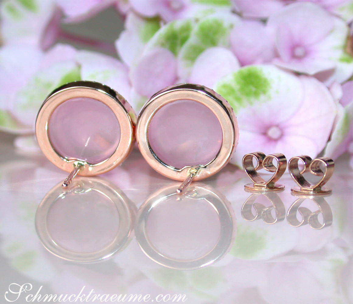 Rosenquarz-Ohrstecker mit Brillanten in Roségold 750, Detailaufnahme mit Blüten im Hintergrund