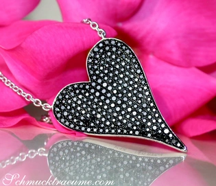 Herz-Anhänger aus Weißgold mit schwarzen Diamanten auf rosa Blüte, Detailaufnahme.