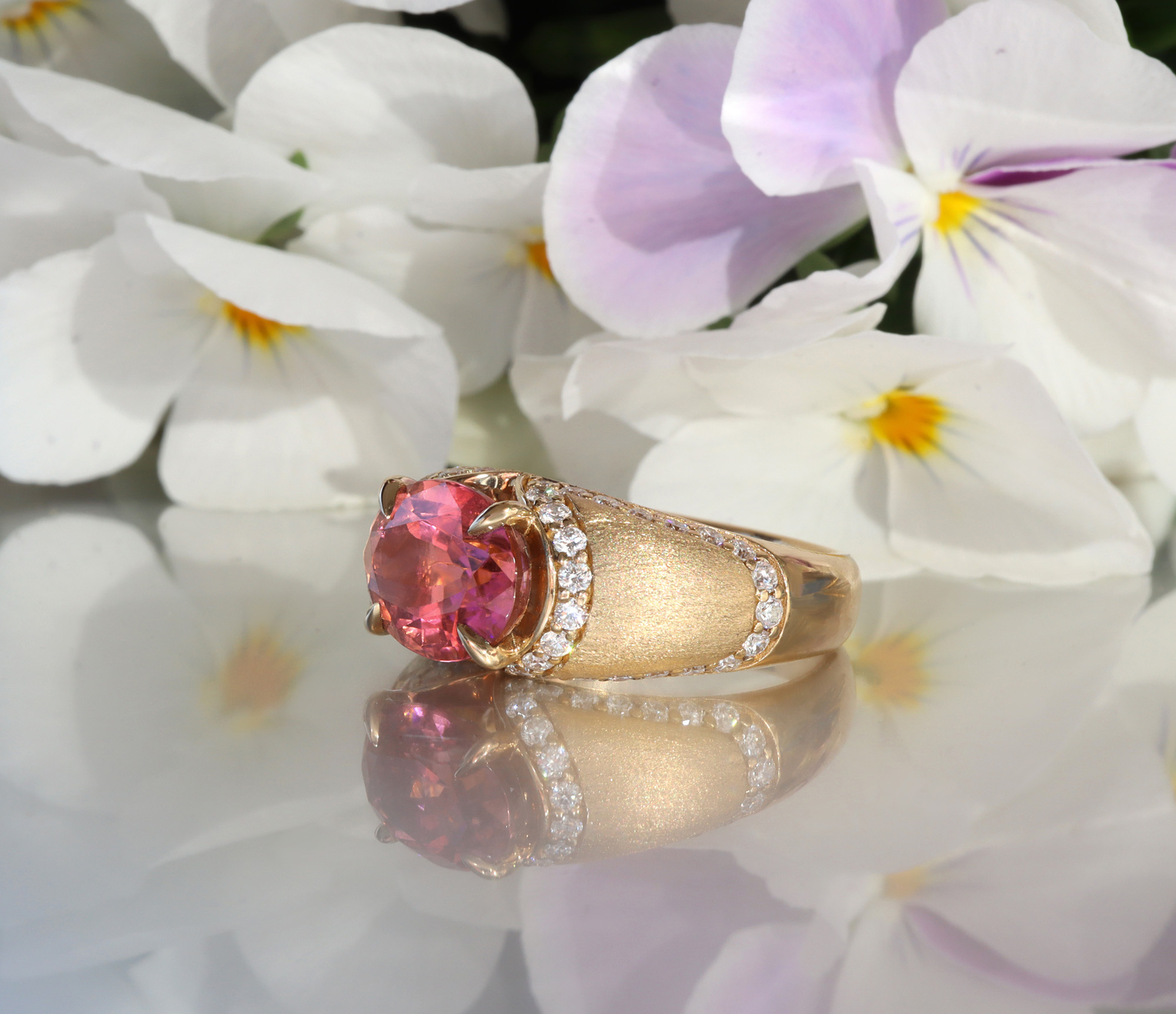 Gelbgold-Ring mit rosa Turmalin und Diamanten, Detailaufnahme auf Blütenhintergrund