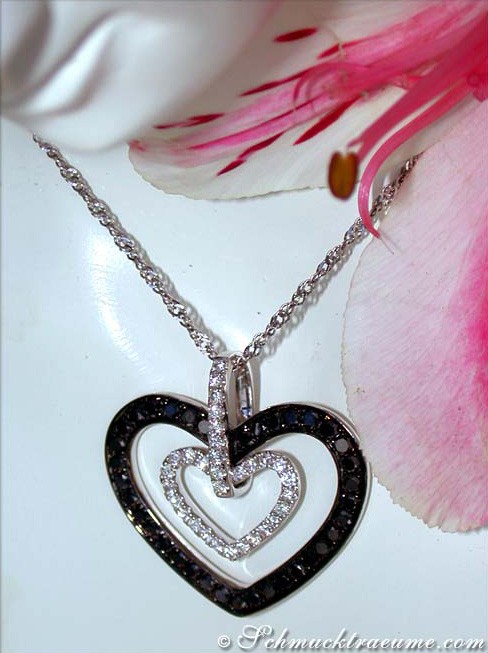 Herz-Anhänger aus Weißgold mit Diamanten, Detailaufnahme, schwebend über Blüte.