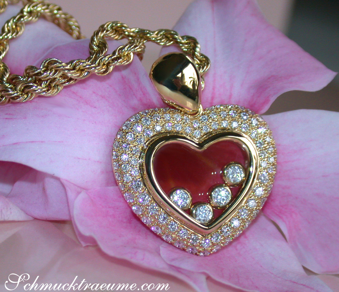 Goldener Herzanhänger mit Diamanten auf Rosenblüte, Detailaufnahme.