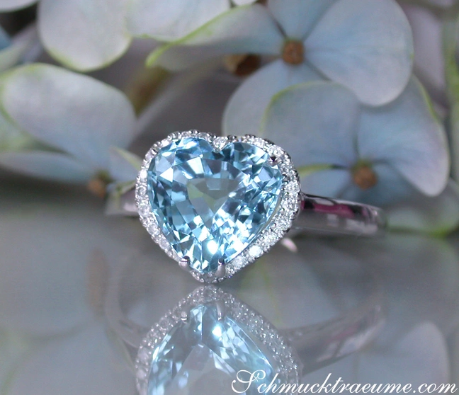 Herzform Aquamarin-Ring mit Diamanten auf Blütenhintergrund Herzform Aquamarin-Ring mit Diamanten auf Blütenhintergrund