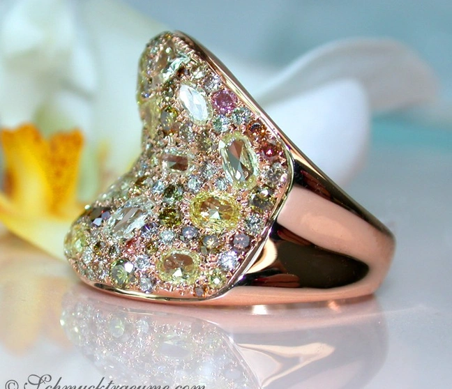 Diamantring in Roségold 750 mit farbigen Diamanten, Detailaufnahme, Orchideenblüte im Hintergrund. Diamantring in Roségold 750 mit farbigen Diamanten, Detailaufnahme, Orchideenblüte im Hintergrund.