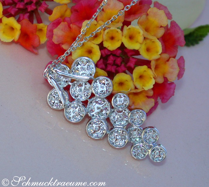 Erlesener Brillanten-Anhänger im Trauben-Design, detailreich, auf Blumenhintergrund.