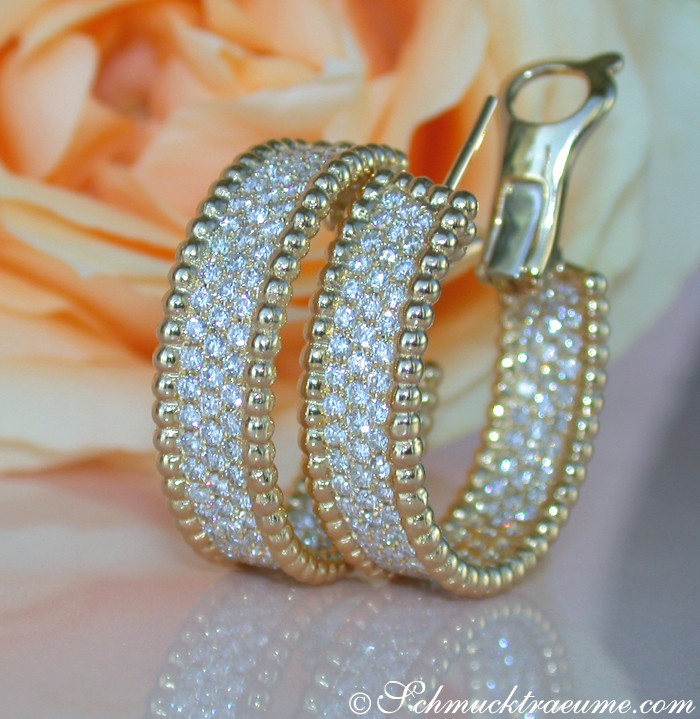 Goldene Creolen mit Brillanten auf Rosenblüte