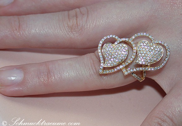 Goldener Herzring mit Diamanten, Detailaufnahme auf der Hand.