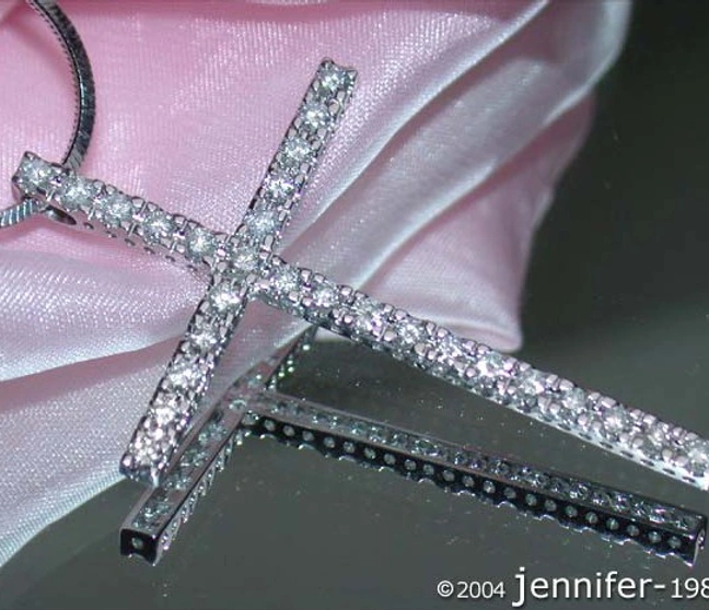 Schlichter Brillanten Kreuz Anhänger auf rosa Stoff, Detailaufnahme, klare Linien, Weißgold 585. Schlichter Brillanten Kreuz Anhänger auf rosa Stoff, Detailaufnahme, klare Linien, Weißgold 585.