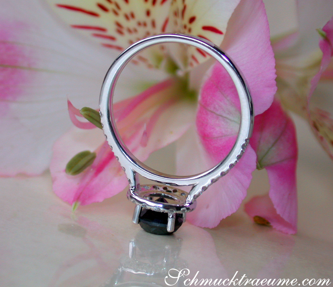 Silberner Ring mit schwarzen Diamanten auf Blütenhintergrund