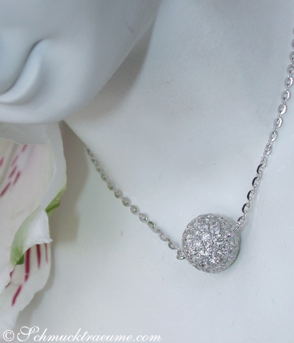 Edle Brillanten Pavé Kugel an Kette, detailreich, zarte Kette, weiße Blume im Hintergrund