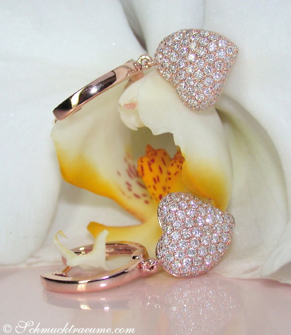 Detailansicht von Herz-Ohrringen in Roségold 750, umgeben von einer Orchideenblüte.