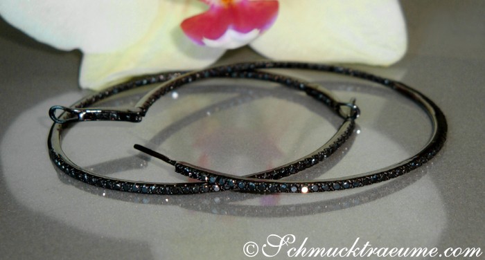 Schwarze Diamant-Creolen auf grauem Hintergrund