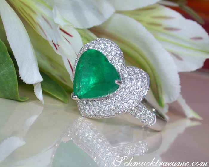 Weißgold Smaragd Herz Ring mit Diamanten auf Blumenhintergrund