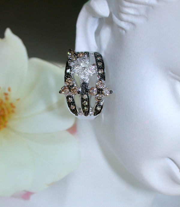 Florale Ohrstecker mit naturbraunen und weißen Diamanten, detailreich, auf Puppenohr getragen, Blüte im Hintergrund.