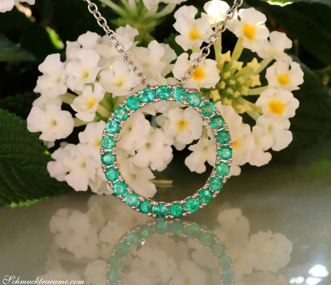 Smaragdkreisanhänger mit feinstem Grün, detailreich, auf weißem Hintergrund mit Blüten. Smaragdkreisanhänger mit feinstem Grün, detailreich, auf weißem Hintergrund mit Blüten.