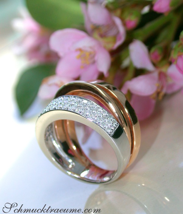 Mehrzeiliger Diamantring in Weiß- und Roségold, Blumen im Hintergrund.