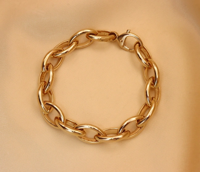 Goldarmband "Navette" in Gelbgold 585, raffiniertes Design, geschlossener Verschluss, glänzend, auf beige Stoff liegend. Goldarmband "Navette" in Gelbgold 585, raffiniertes Design, geschlossener Verschluss, glänzend, auf beige Stoff liegend.