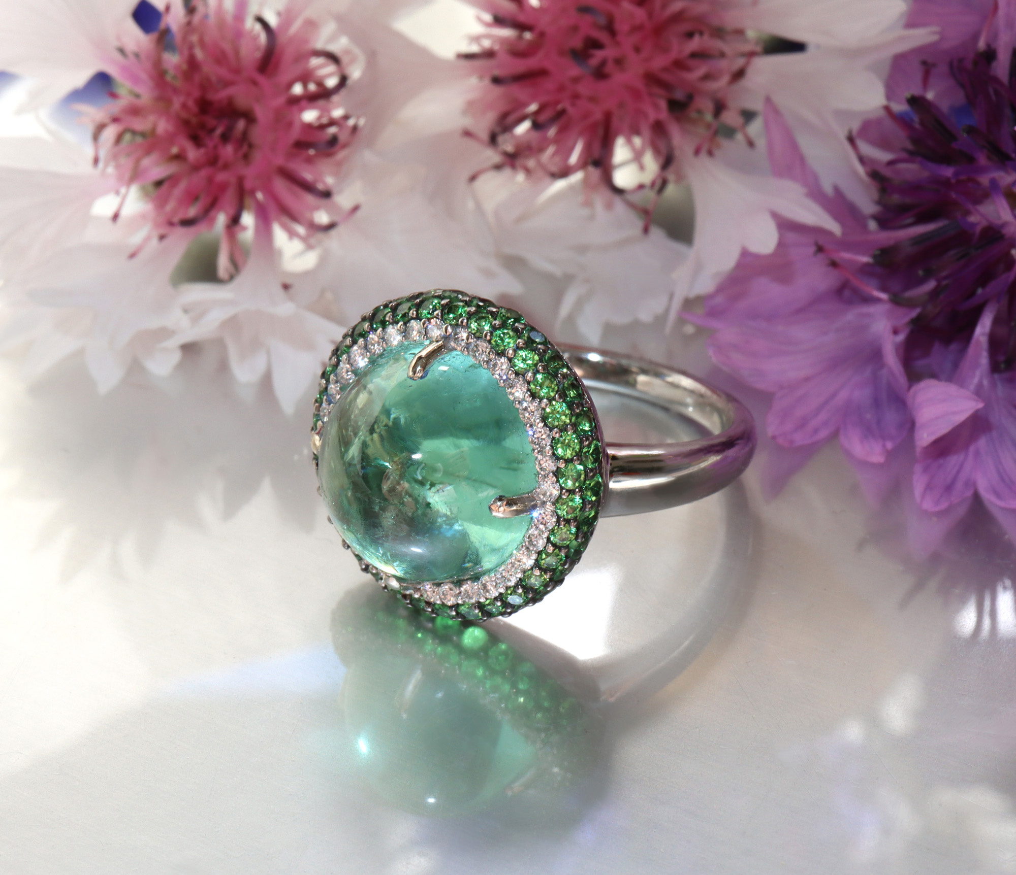 Minz-Turmalin-Ring mit Tsavorite und Brillanten, detailreich, auf Blumenhintergrund.