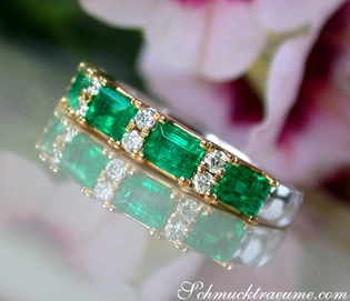 Smaragd-Bandring mit Brillanten, goldene Details, Blumenhintergrund.