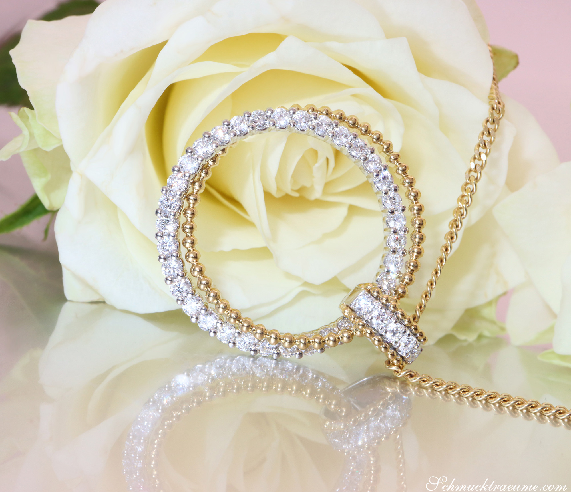 Weißgold-Anhänger mit funkelnden Brillanten und Kugelkette, vor weißer Rose.