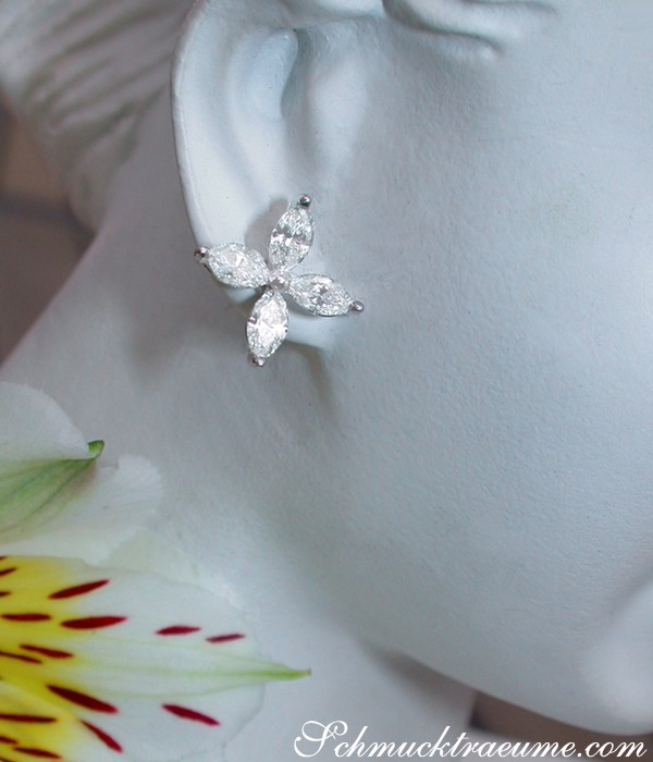 Weißgold-Ohrring mit Marquise-Diamanten im Blüten-Design, zarte Blume im Hintergrund.