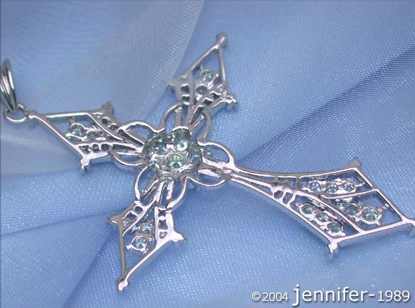 Kreuzanhänger aus Weißgold 750 mit Brillanten, filigraner Struktur, auf blauem Stoff liegend