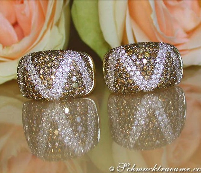 Goldene Zick-Zack-Ohrstecker mit braunen und weißen Brillanten auf Rosenhintergrund Goldene Zick-Zack-Ohrstecker mit braunen und weißen Brillanten auf Rosenhintergrund