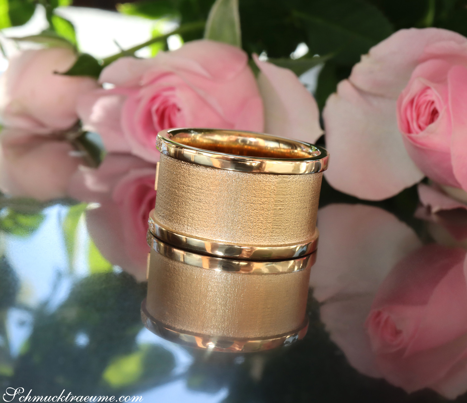 Goldener Ring mit Diamanten vor Rosenblüten